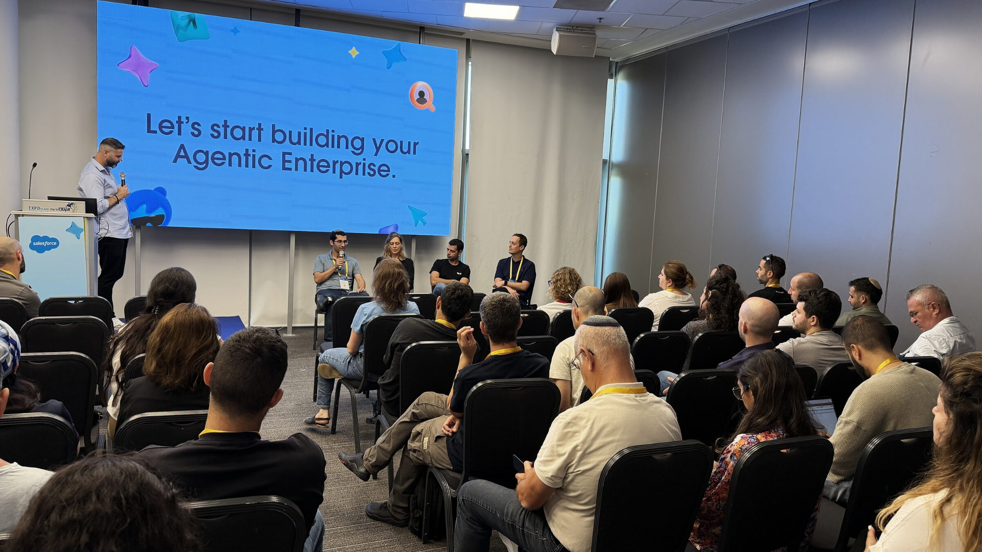 Seated audience at a Salesforce event watching a panel Liron Kaplan is hosting