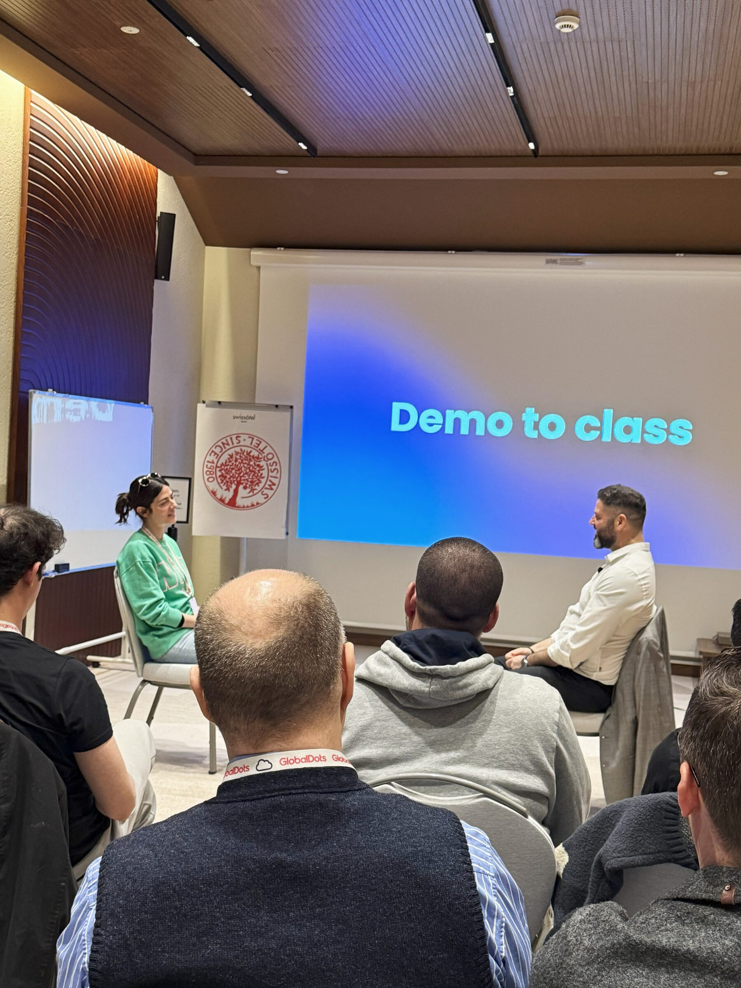 Liron Kaplan running a live 'Demo to class' role-play with a participant in front of a seated training group