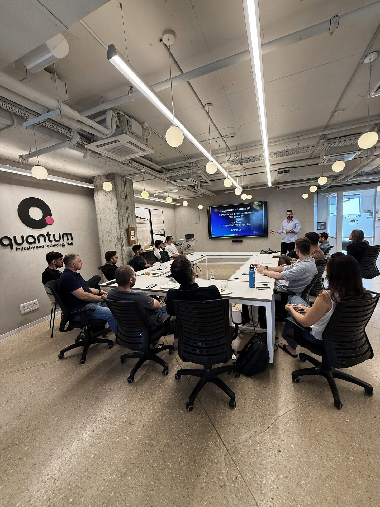Liron Kaplan leading a GTM workshop around a boardroom table at the Quantum industry and technology hub