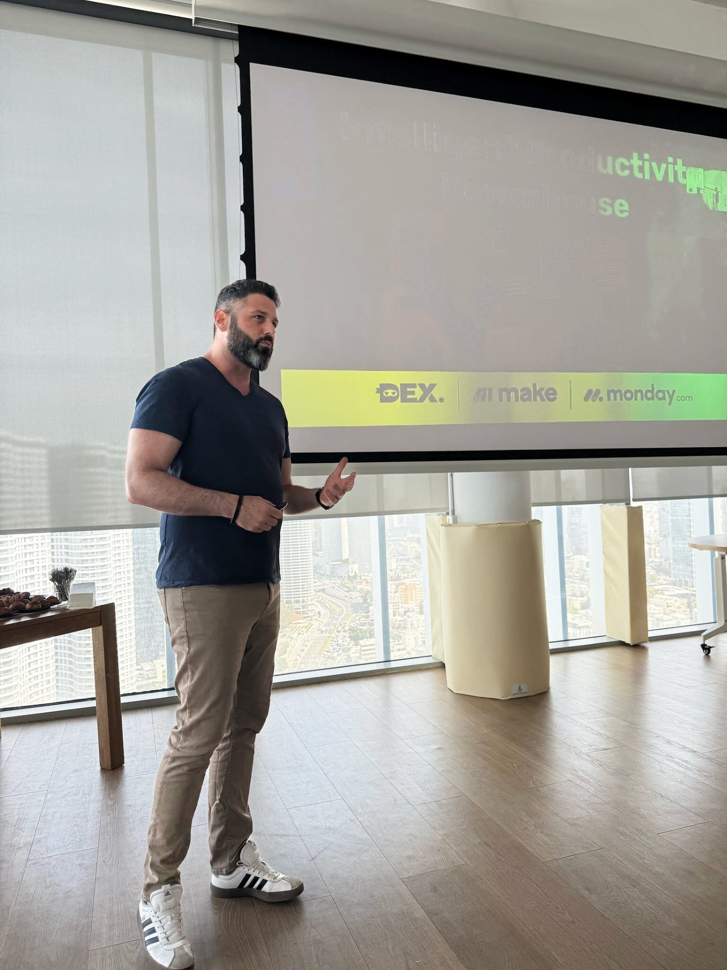 Liron Kaplan running a working session with a team in a Tel Aviv office, presenting to the room beside a projector screen