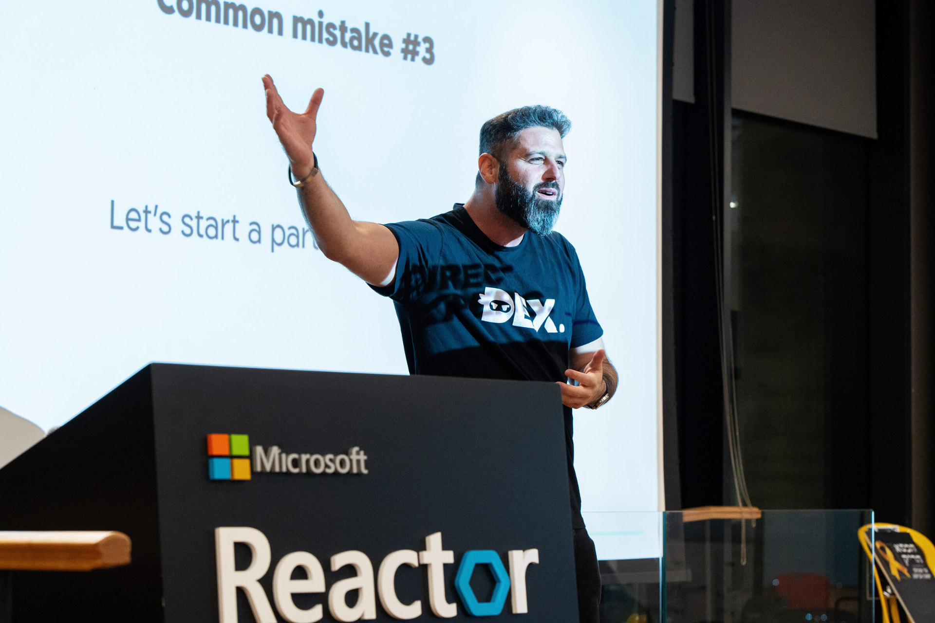 Liron Kaplan presenting from the Microsoft Reactor stage to a full audience of seated attendees